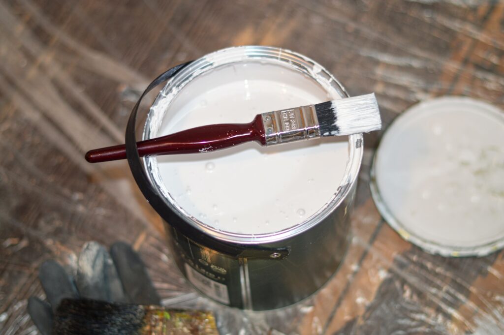 a paint bucket with open lid and paint brush across the top
