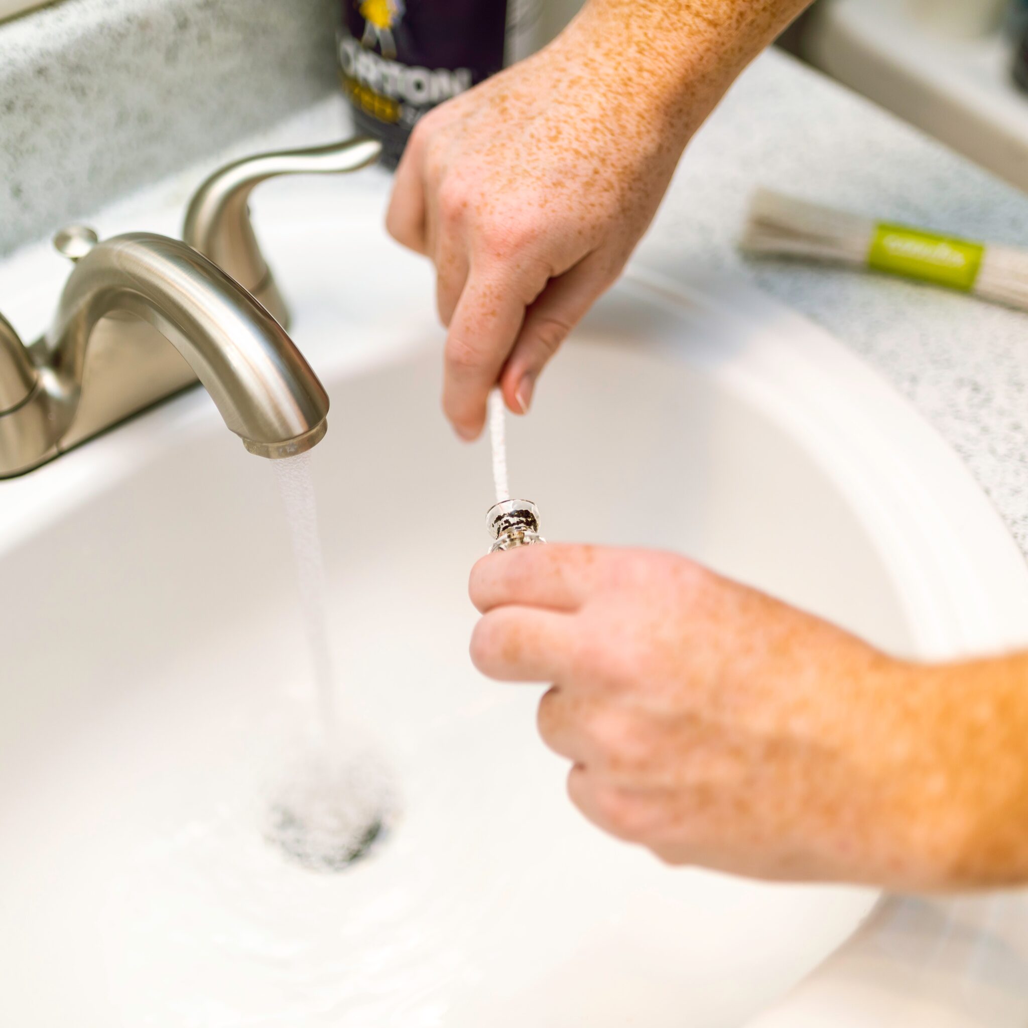 person cleaning a plumbing part in sink
