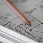 Close-up of architectural blueprint plans with pencil and ruler, representing zoning and site plan review