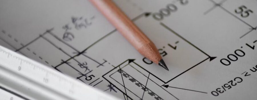 Close-up of architectural blueprint plans with pencil and ruler, representing zoning and site plan review