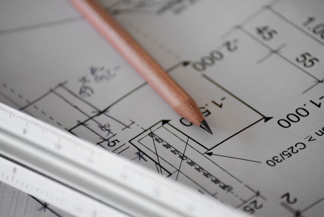 Close-up of architectural blueprint plans with pencil and ruler, representing zoning and site plan review