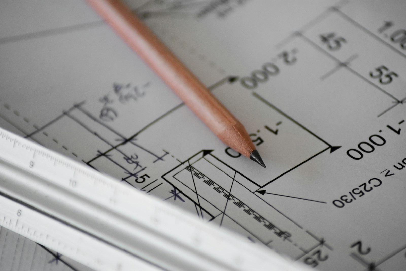 Close-up of a dimensioned architectural plan being reviewed with a pencil and scale ruler during ADU permit preparation