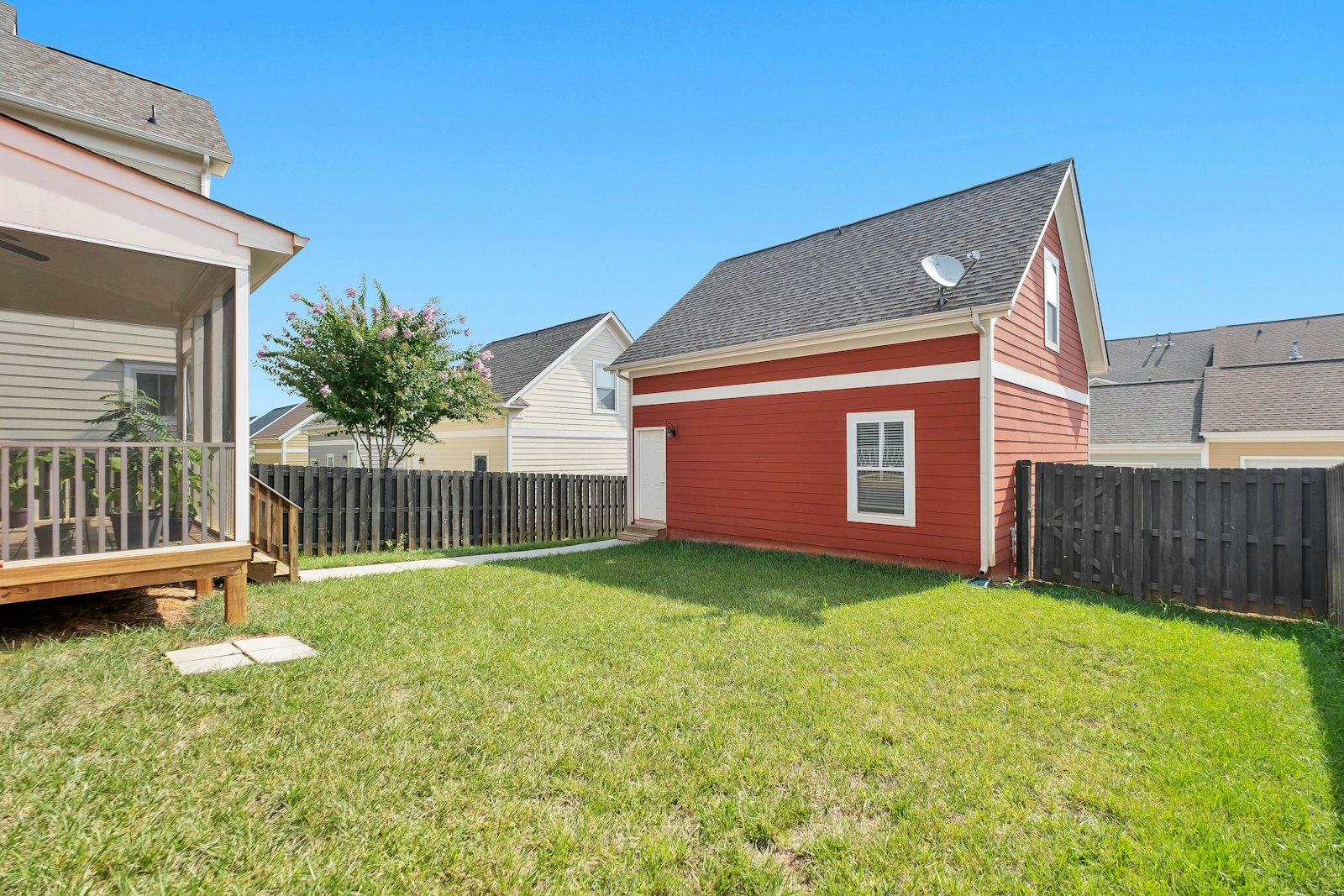 Small detached accessory dwelling unit set back from a fenced rear property line in a California backyard