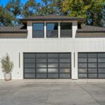 Modern single-family home with two glass-panel garage doors and a concrete driveway