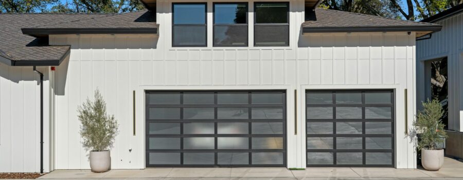 Modern single-family home with two glass-panel garage doors and a concrete driveway